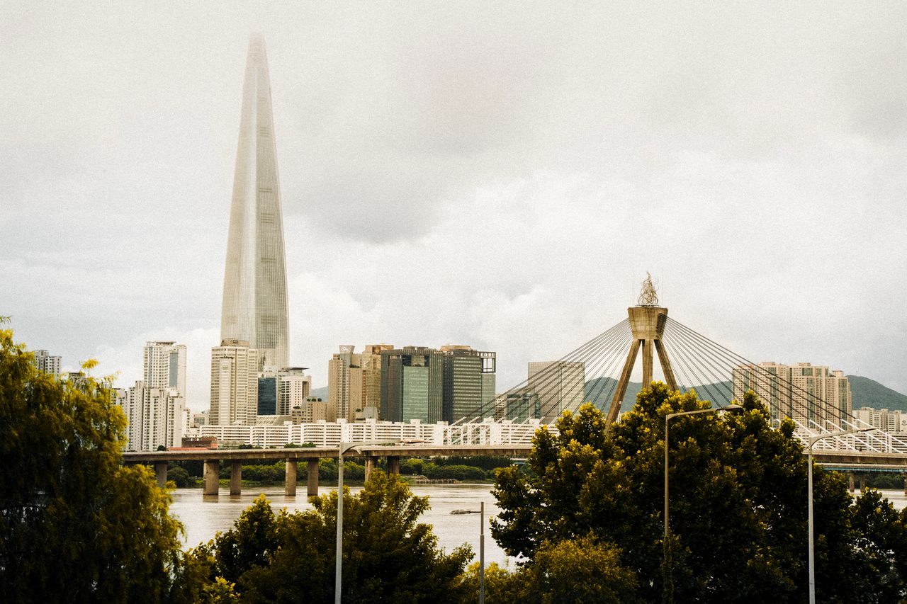 View of Lotte World Tower and Seoul skyline, featuring modern skyscrapers and a cloudy sky.